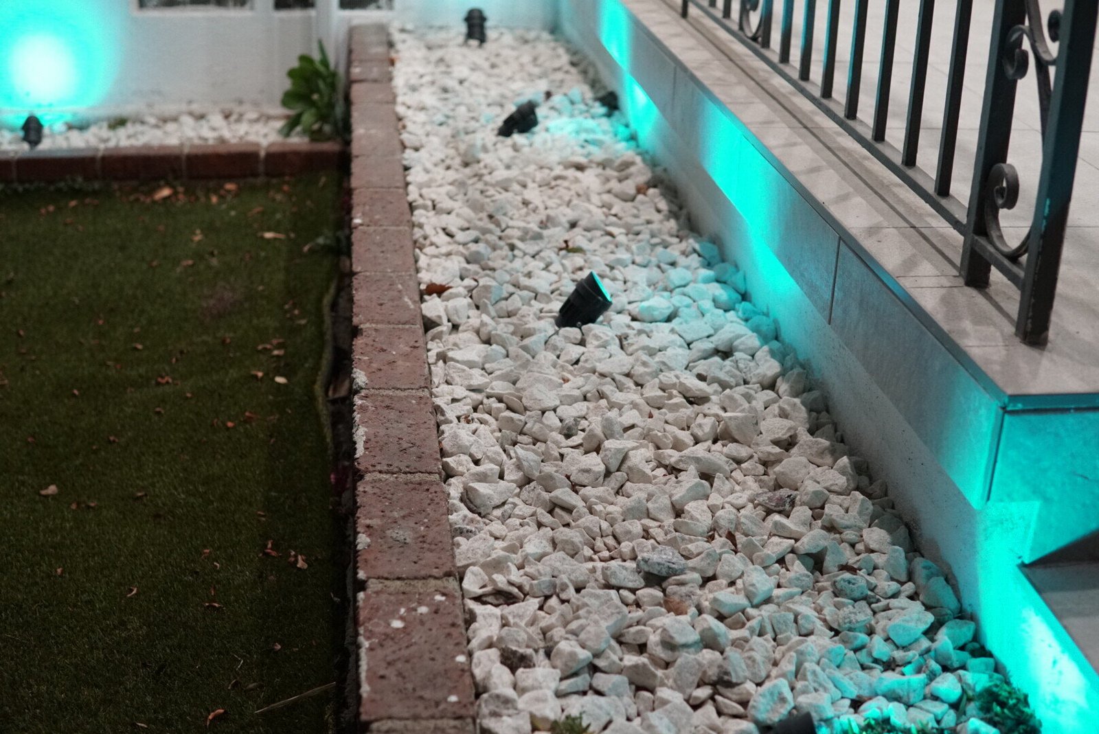 Elegant garden lighting with LED spotlights illuminating a stone-lined path and railing.