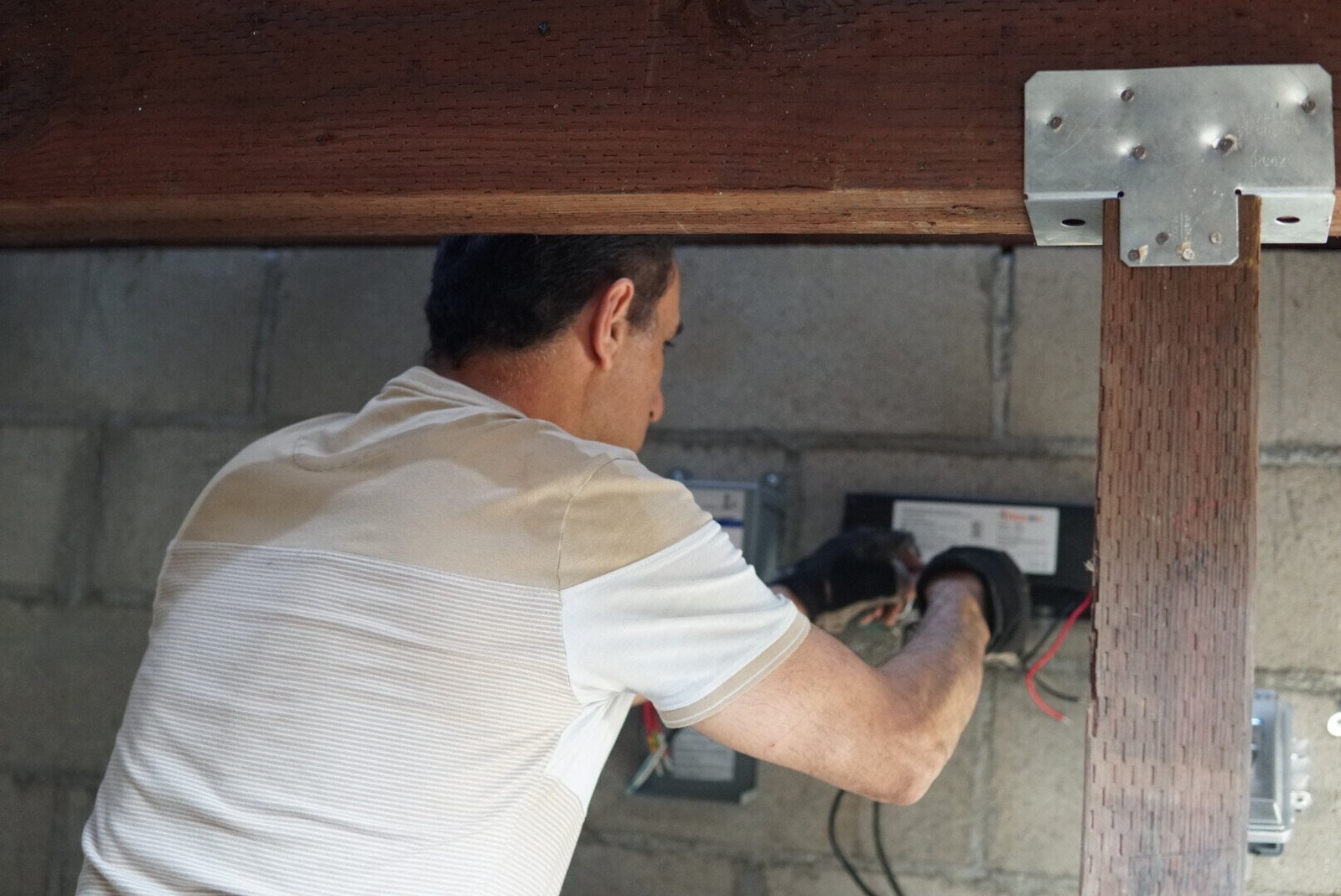 Technician installing a low voltage lighting converter outdoors for an energy-efficient lighting system.