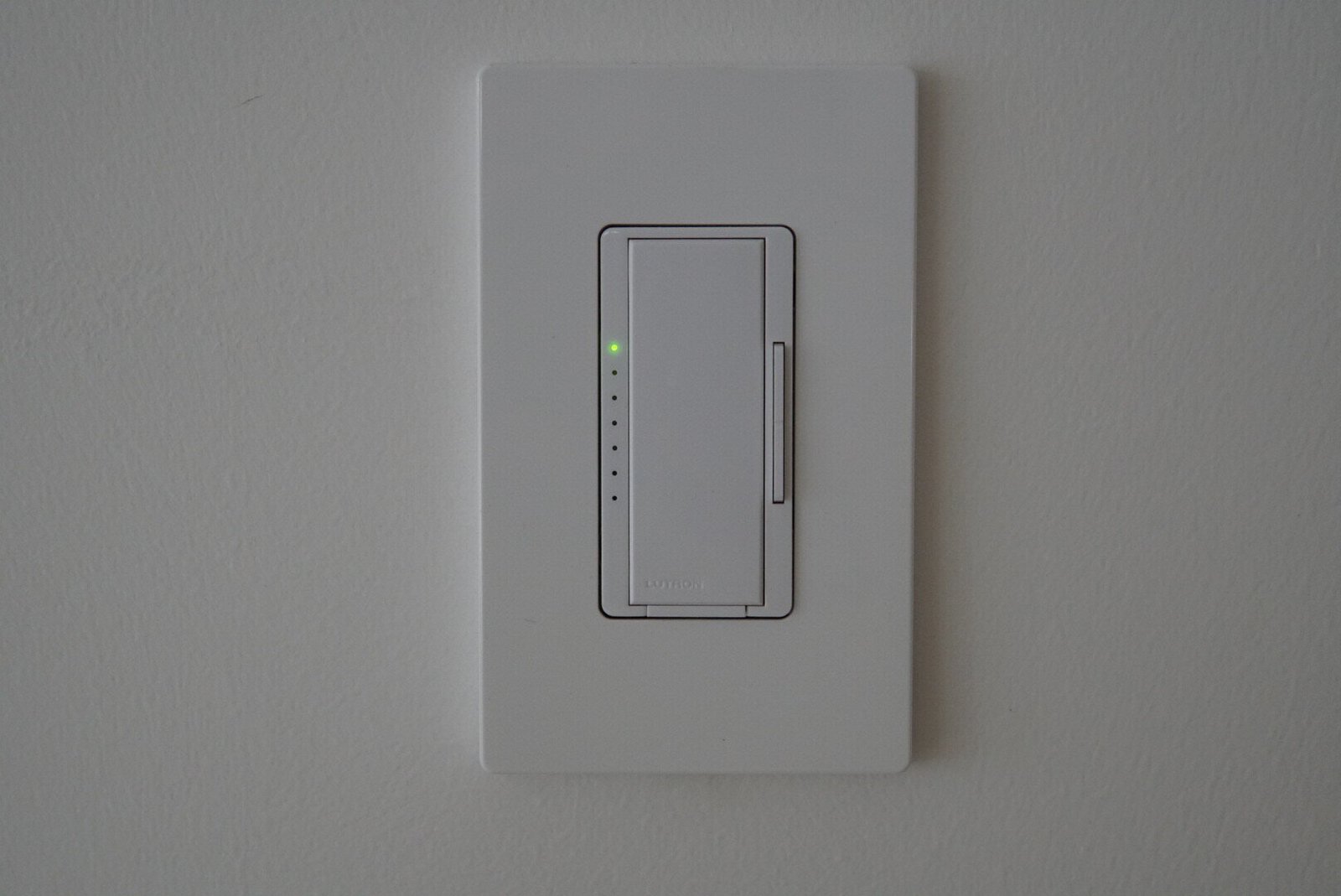 Modern dimmer switch on a sleek white wall, designed for adjusting light intensity in residential spaces.