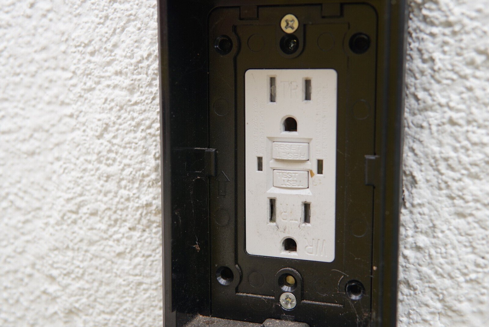 Close-up of a GFCI electrical outlet installed on a white wall, designed for safe and reliable use in basements and attics.